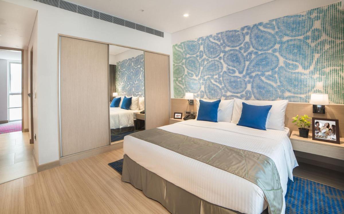 a bedroom with a large bed with blue pillows at Citadines OMR Chennai in Chennai a bedroom with a large bed with blue pillows at Citadines OMR Chennai in Chennai