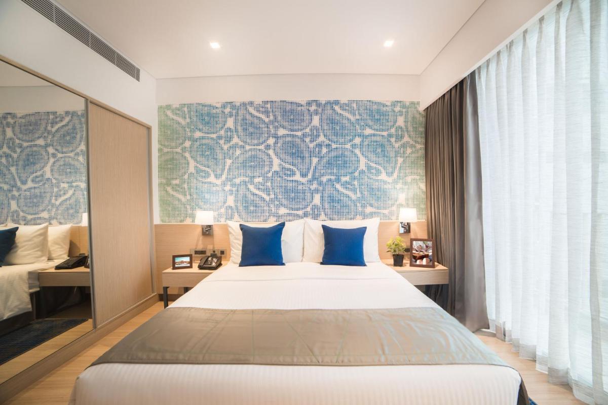 a bedroom with a large bed with blue pillows at Citadines OMR Chennai in Chennai a bedroom with a large bed with blue pillows at Citadines OMR Chennai in Chennai