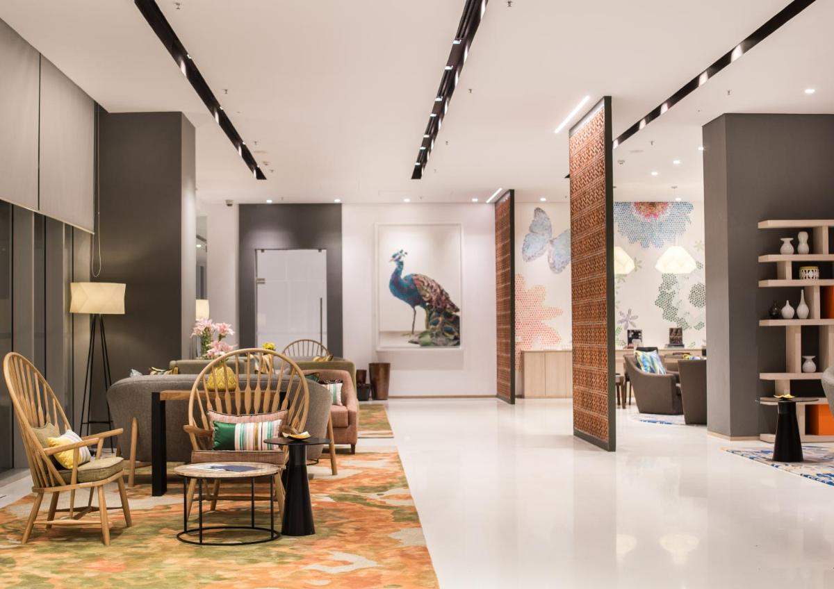 a lobby with chairs and a peacock painting on the wall at Citadines OMR Chennai in Chennai a lobby with chairs and a peacock painting on the wall at Citadines OMR Chennai in Chennai