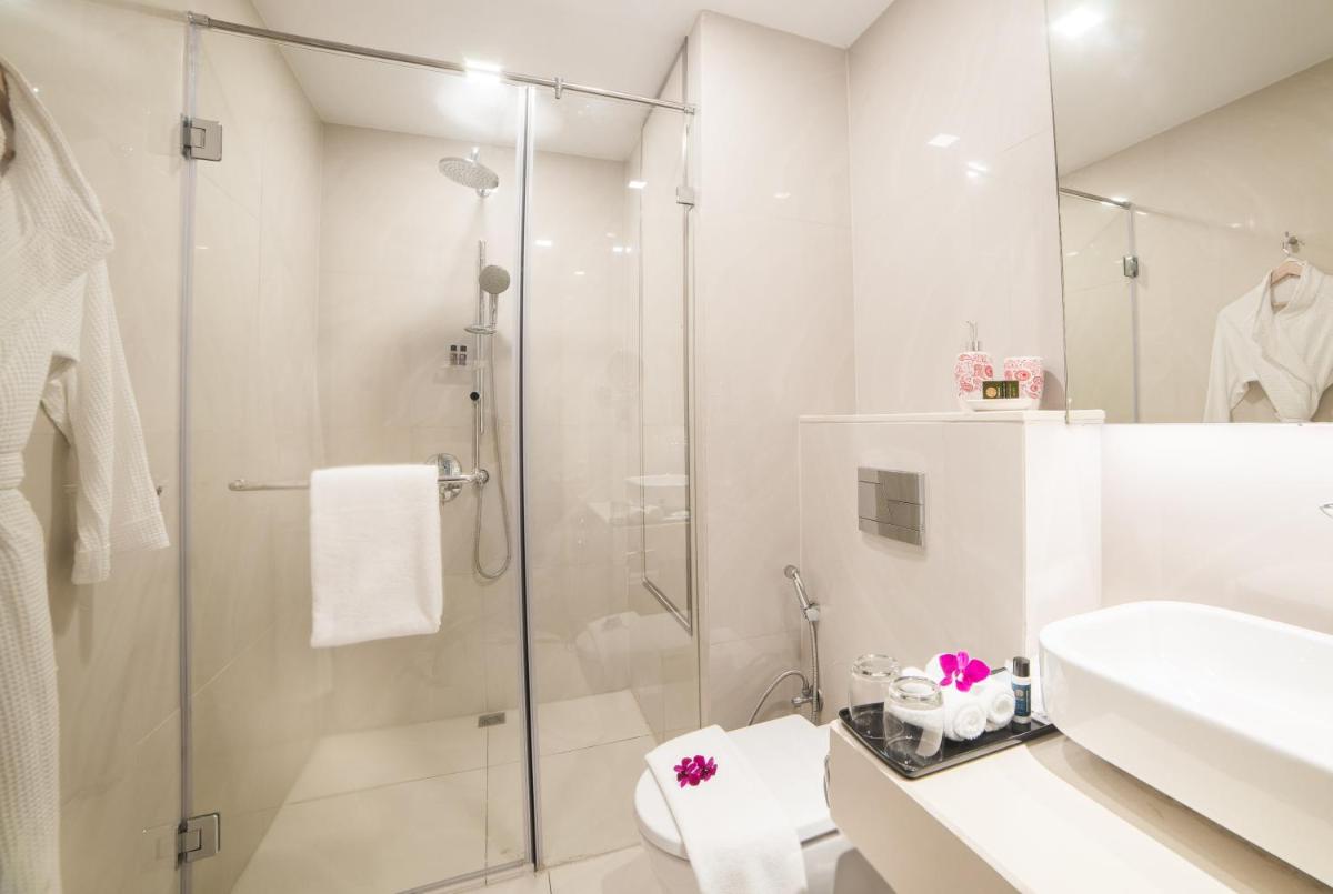 a white bathroom with a shower and a sink at Citadines OMR Chennai in Chennai a white bathroom with a shower and a sink at Citadines OMR Chennai in Chennai