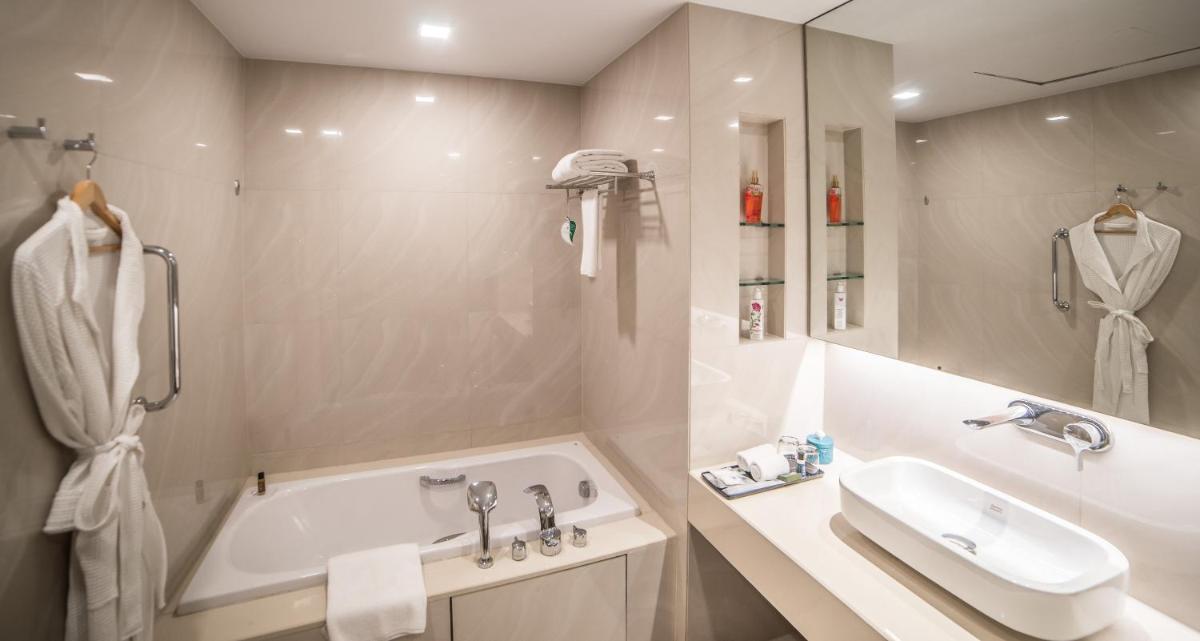 a white bathroom with a tub and a sink at Citadines OMR Chennai in Chennai a white bathroom with a tub and a sink at Citadines OMR Chennai in Chennai