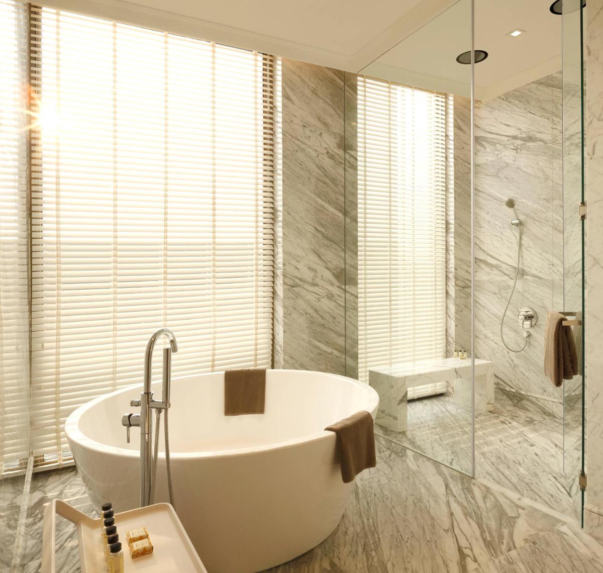 a bathroom with a bath tub and a shower at Roseate House New Delhi in New Delhi a bathroom with a bath tub and a shower at Roseate House New Delhi in New Delhi