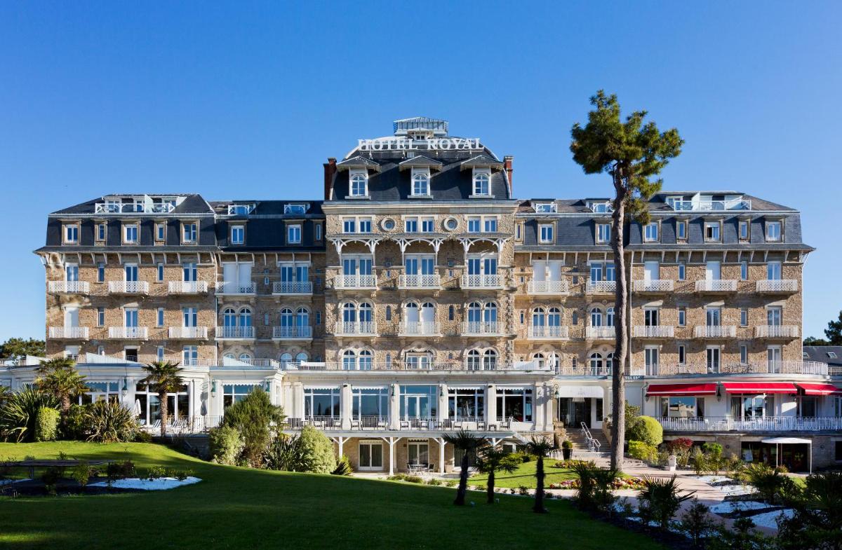 un grand bâtiment avec un palmier devant dans l'établissement Hôtel Barrière Le Royal La Baule, à La Baule
