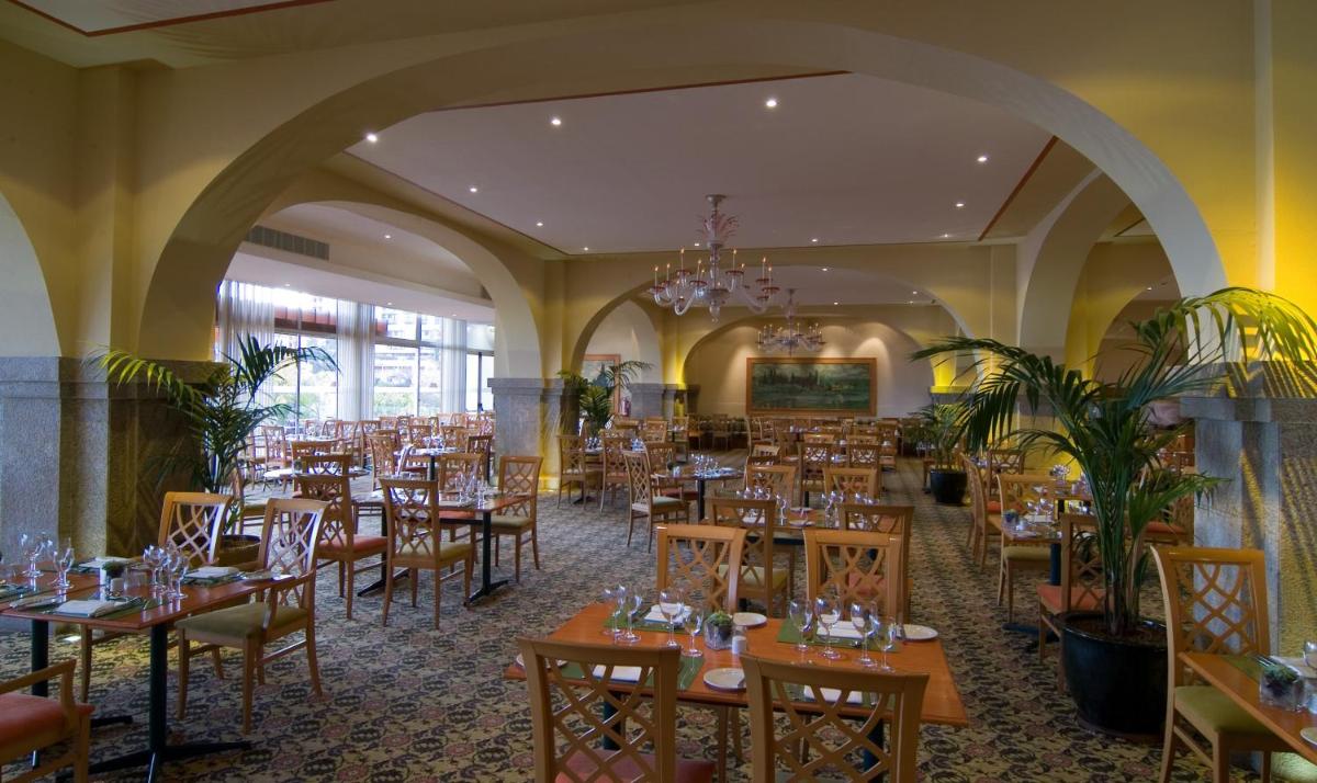 uma sala de jantar com mesas e cadeiras e um lustre em Pestana Madeira Beach Club no Funchal