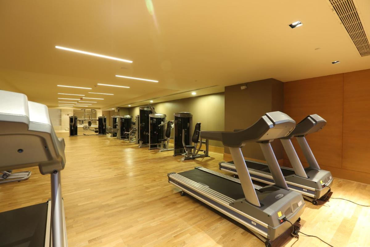 a gym with a row of treadms and cardio machines at Feathers- A Radha Hotel, Chennai in Chennai