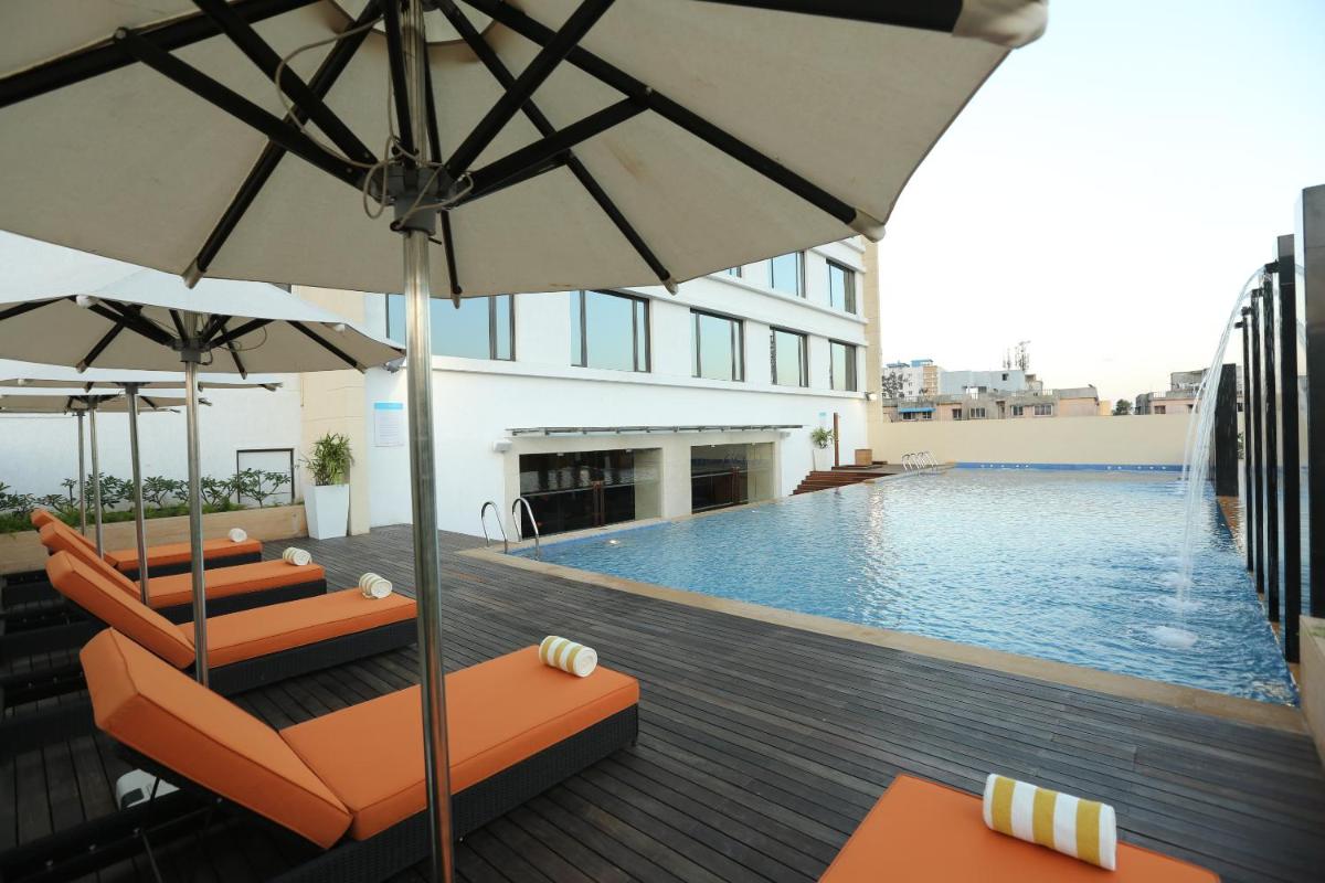 a swimming pool with chairs and umbrellas on a building at Feathers- A Radha Hotel, Chennai in Chennai