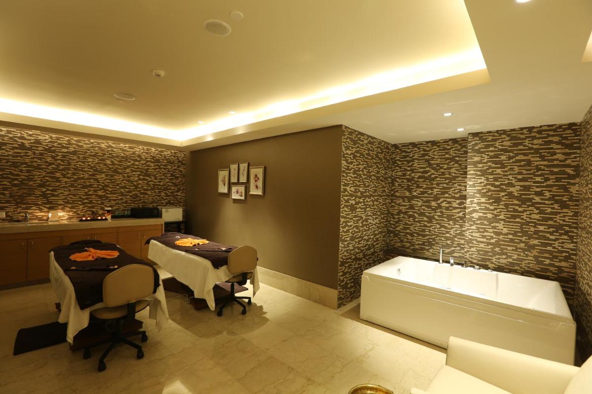 a bathroom with a tub and a table and chairs at Feathers- A Radha Hotel, Chennai in Chennai