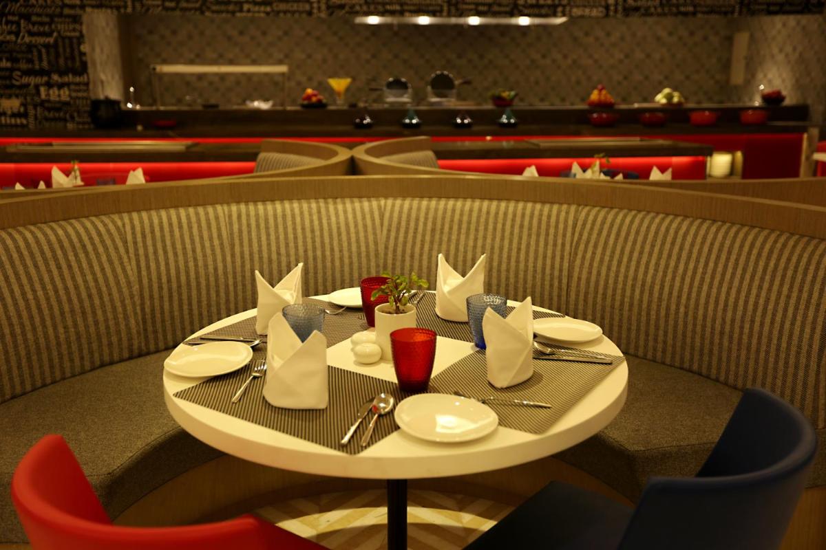 a table with plates and napkins on it in a restaurant at Ramada by Wyndham Lucknow Hotel and Convention Center in Lucknow