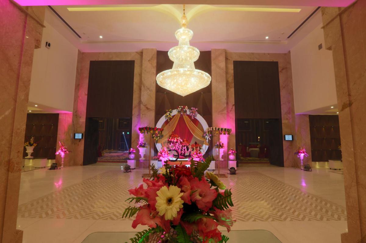 a lobby with a chandelier and flowers in a room at Ramada by Wyndham Lucknow Hotel and Convention Center in Lucknow