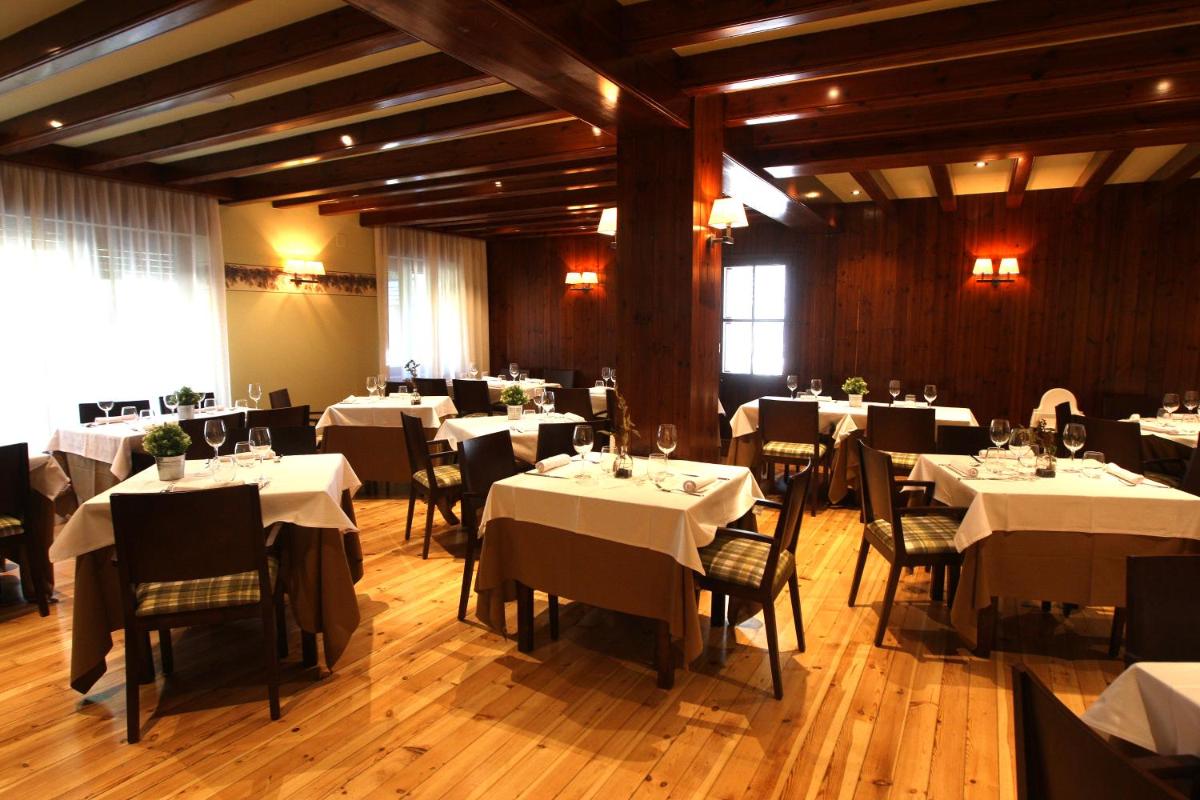 Un comedor con mesas y sillas blancas. en Hotel & Spa Real Villa Anayet, en Canfranc-Estación