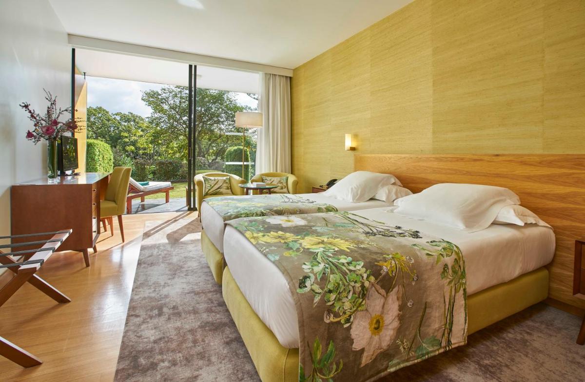 um quarto de hotel com uma cama grande e uma escrivaninha em Quinta da Casa Branca - Small Luxury Hotels of the World no Funchal