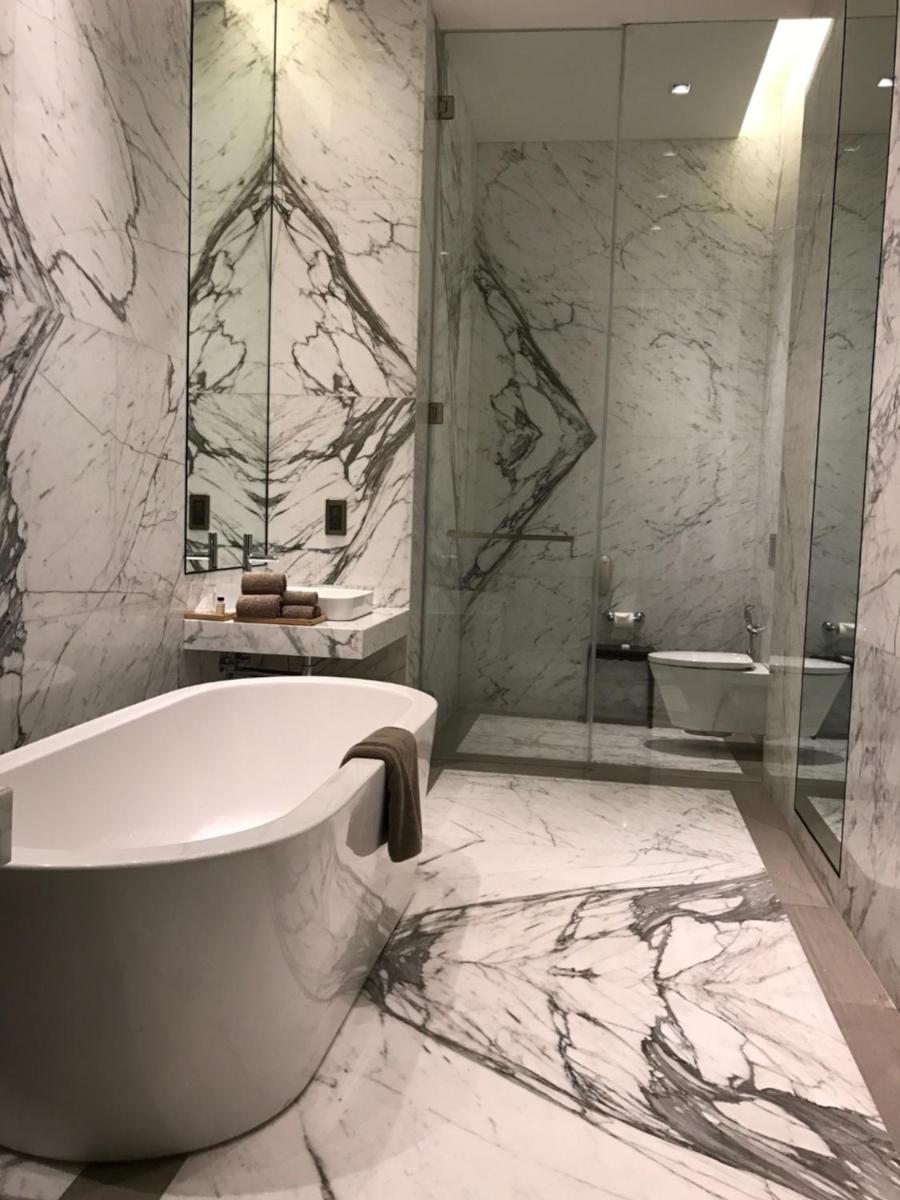 a bathroom with a tub and a glass shower at Roseate House New Delhi in New Delhi a bathroom with a tub and a glass shower at Roseate House New Delhi in New Delhi