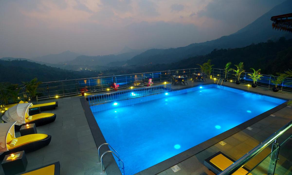 a hotel swimming pool with mountains in the background at The Panoramic Getaway in Munnar