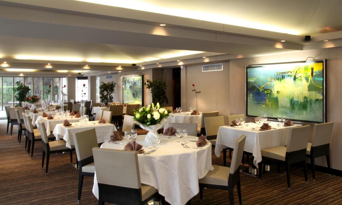 une salle à manger avec des tables et des chaises blanches dans l'établissement Amirauté Hôtel Golf Deauville, à Deauville 37 autres photos