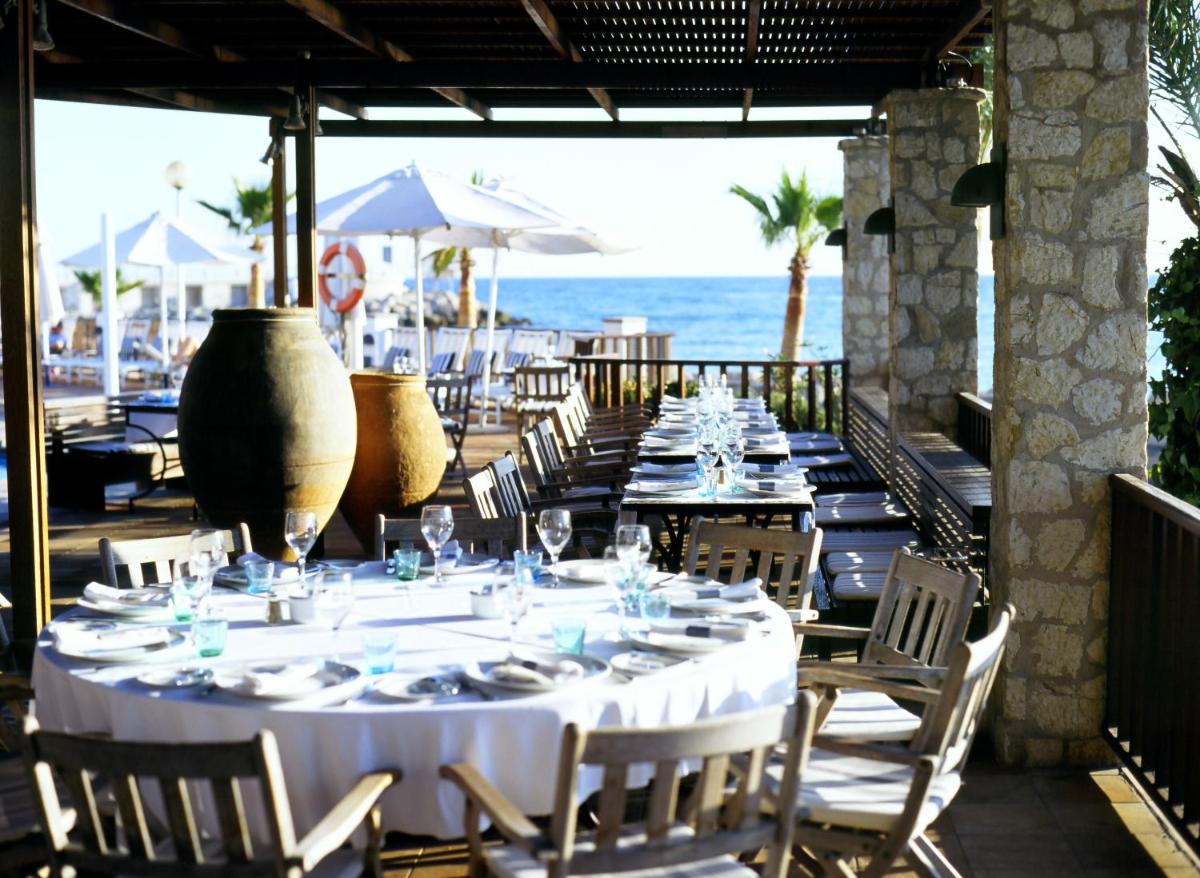 una mesa larga con mesas y sillas blancas y el océano en Portixol Hotel & Restaurant, en Palma de Mallorca