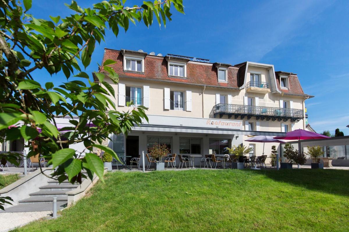 un bâtiment avec une pelouse devant dans l'établissement Logis Hotel Restaurant Spa Beau Site, à Luxeuil-les-Bains