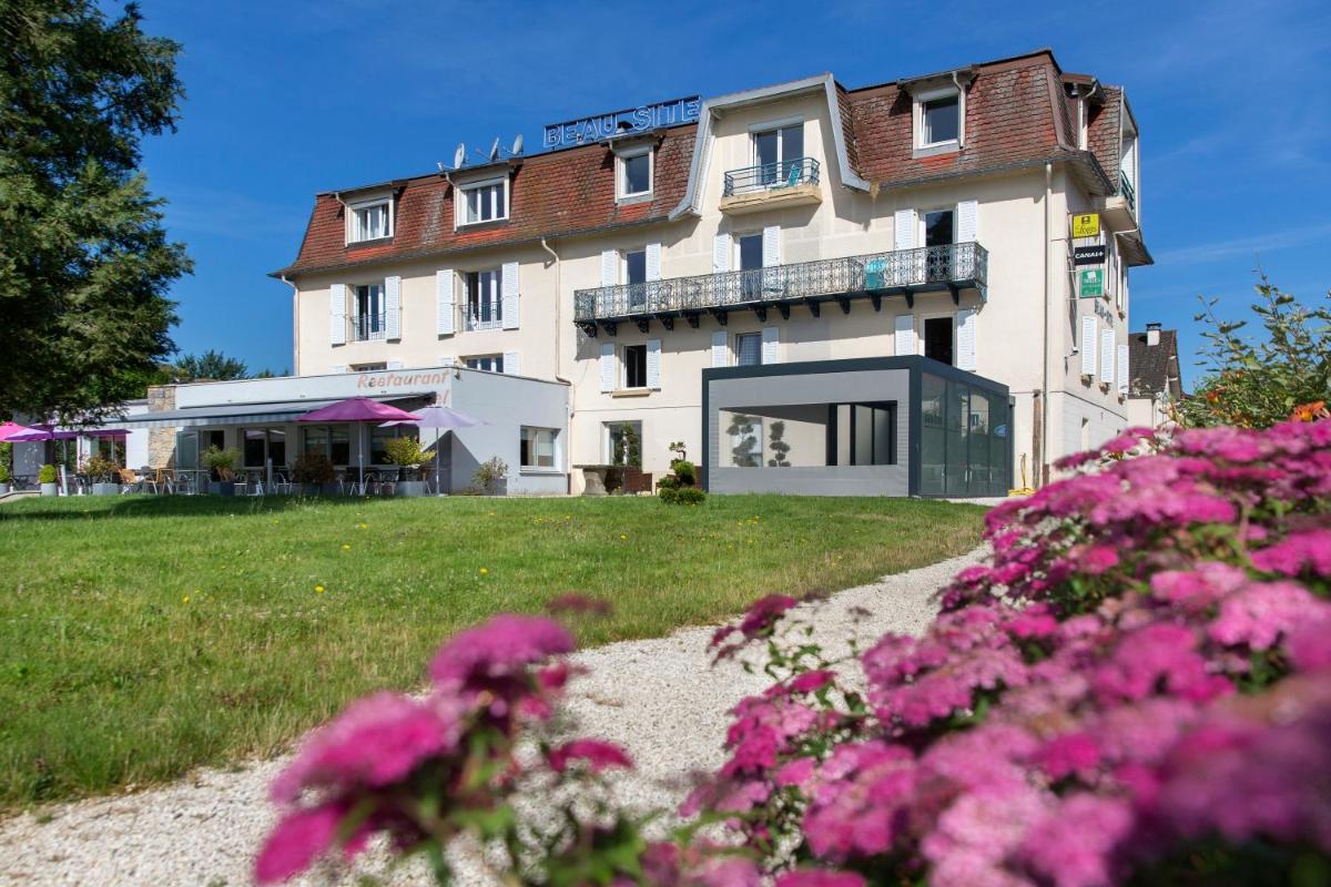 un bâtiment avec des fleurs roses devant lui dans l'établissement Logis Hotel Restaurant Spa Beau Site, à Luxeuil-les-Bains