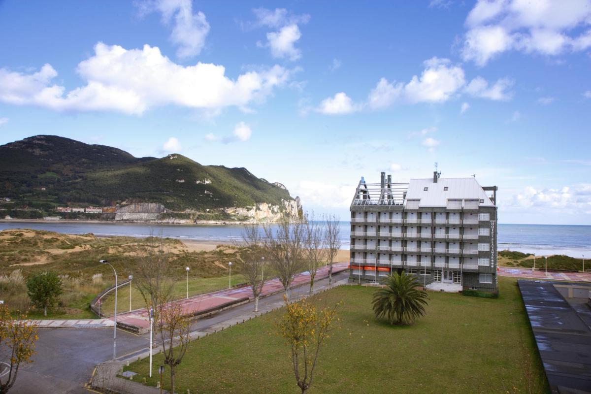 Un edificio al lado de la playa con el océano. en Hotel Playamar Spa, en Laredo