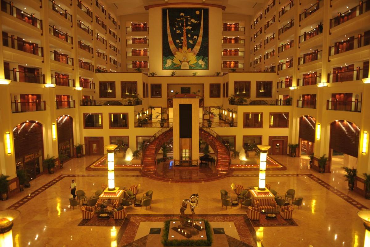 an empty lobby of a hotel with tables and chairs at The Lalit Mumbai in Mumbai