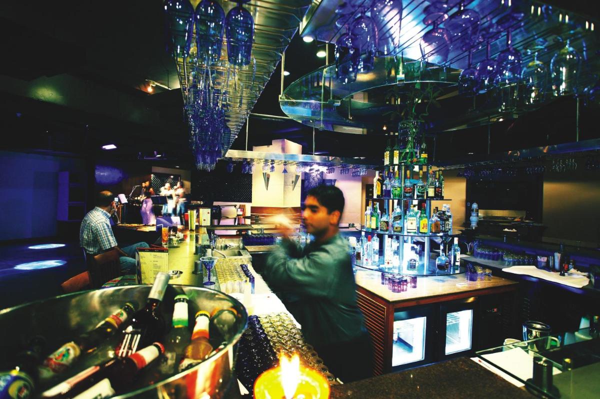 a man sitting at a bar in a restaurant at The Lalit Mumbai in Mumbai