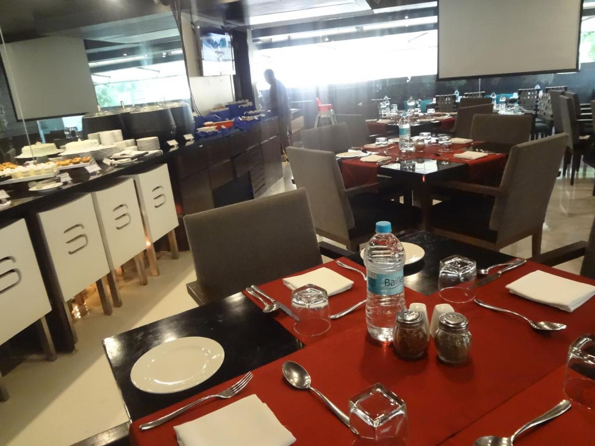 a restaurant with tables and chairs with a bottle of water at Svenska Design Hotel in Mumbai