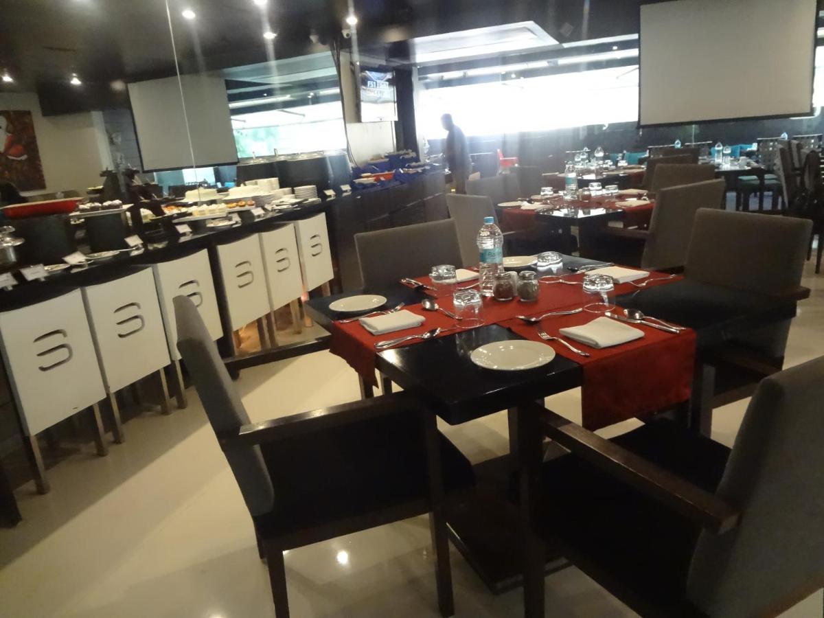 a dining room with a table and chairs in a restaurant at Svenska Design Hotel in Mumbai