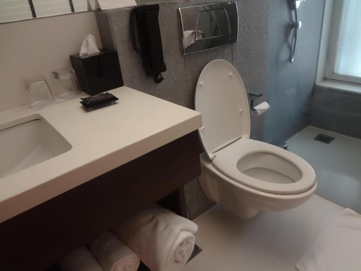 a bathroom with a white toilet and a sink at Svenska Design Hotel in Mumbai