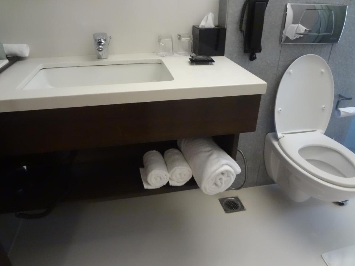 a bathroom with a sink and a toilet and towels at Svenska Design Hotel in Mumbai