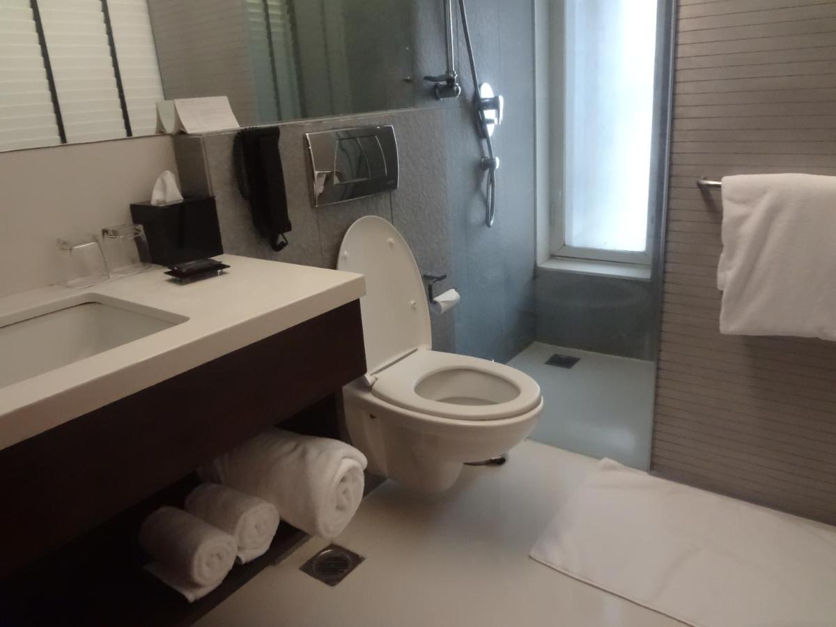 a bathroom with a white toilet and a sink at Svenska Design Hotel in Mumbai
