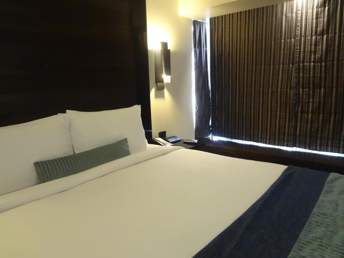 a bed in a hotel room with a window at Svenska Design Hotel in Mumbai