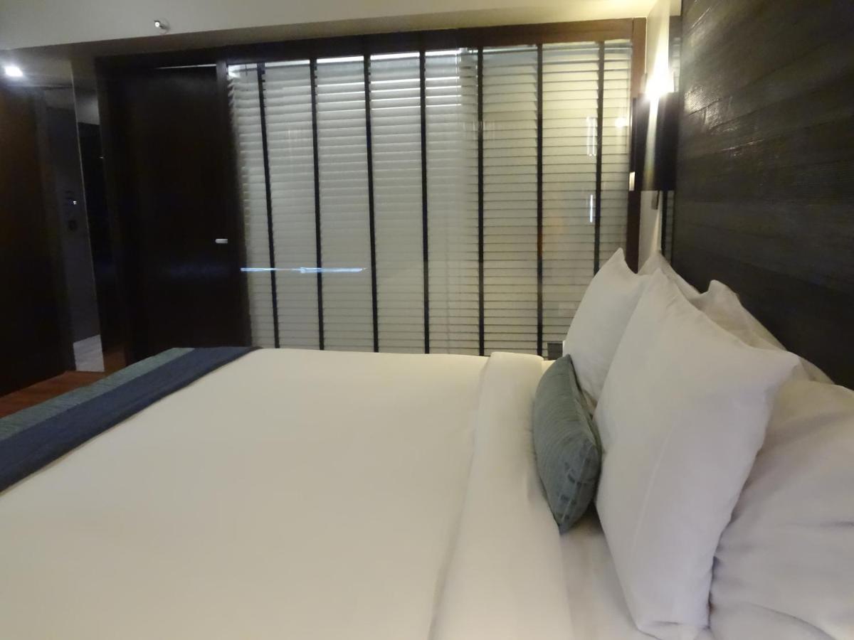 a bedroom with a bed with white pillows and a window at Svenska Design Hotel in Mumbai
