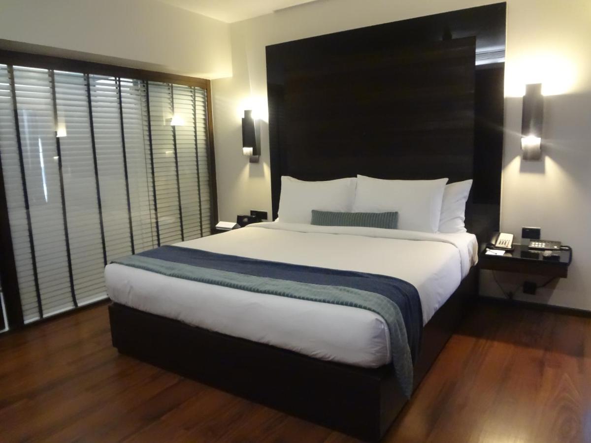 a bedroom with a large bed with a large headboard at Svenska Design Hotel in Mumbai