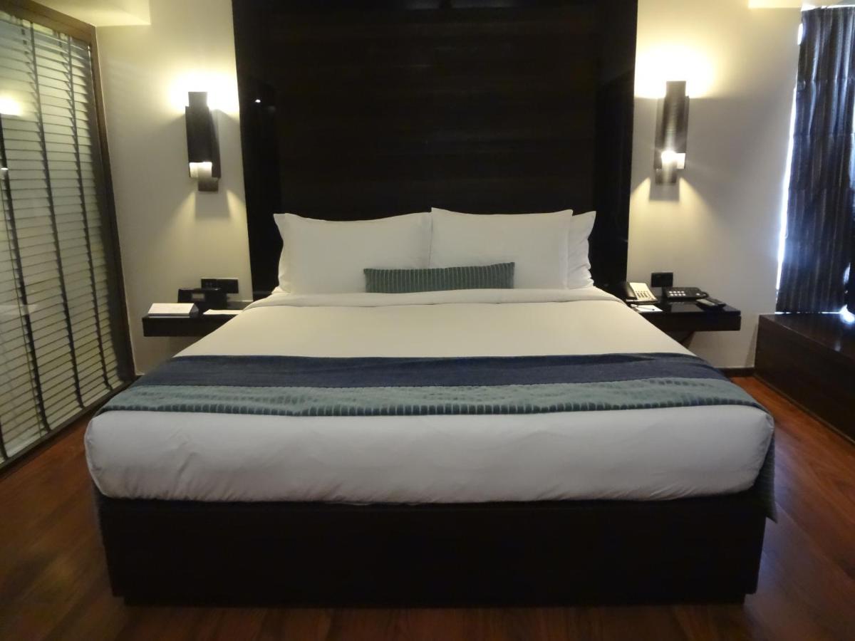 a bedroom with a large bed with a black headboard at Svenska Design Hotel in Mumbai