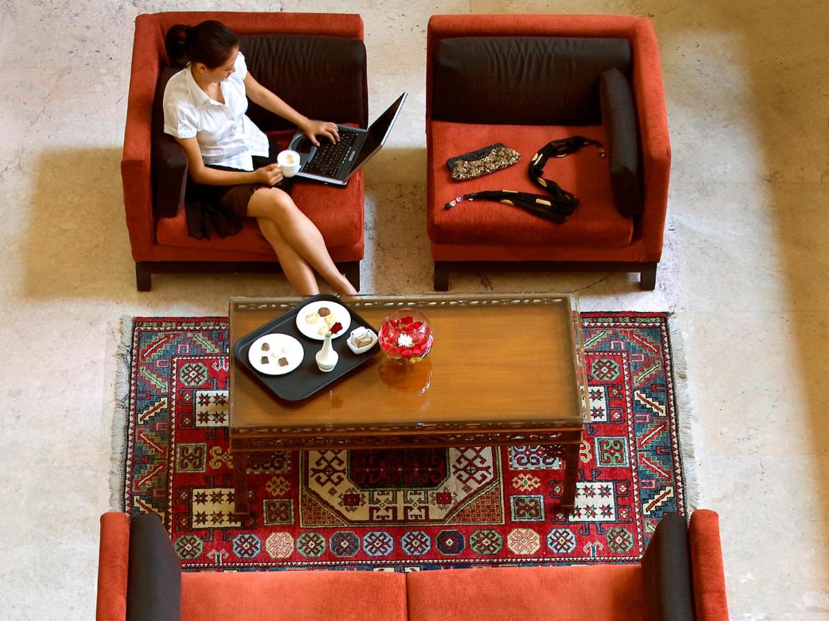 a woman sitting in chairs with a laptop on a table at The Lalit Mumbai in Mumbai