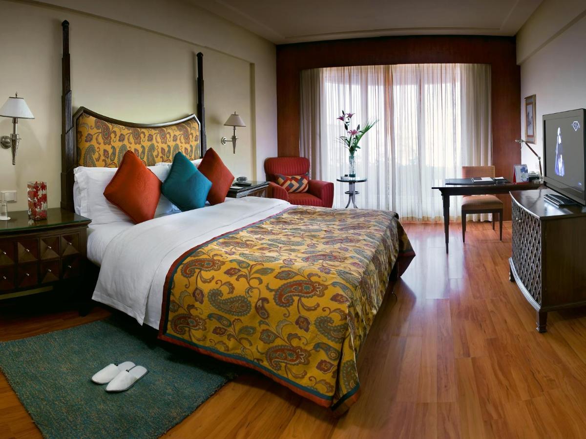 a hotel room with a bed and a desk at The Lalit Mumbai in Mumbai