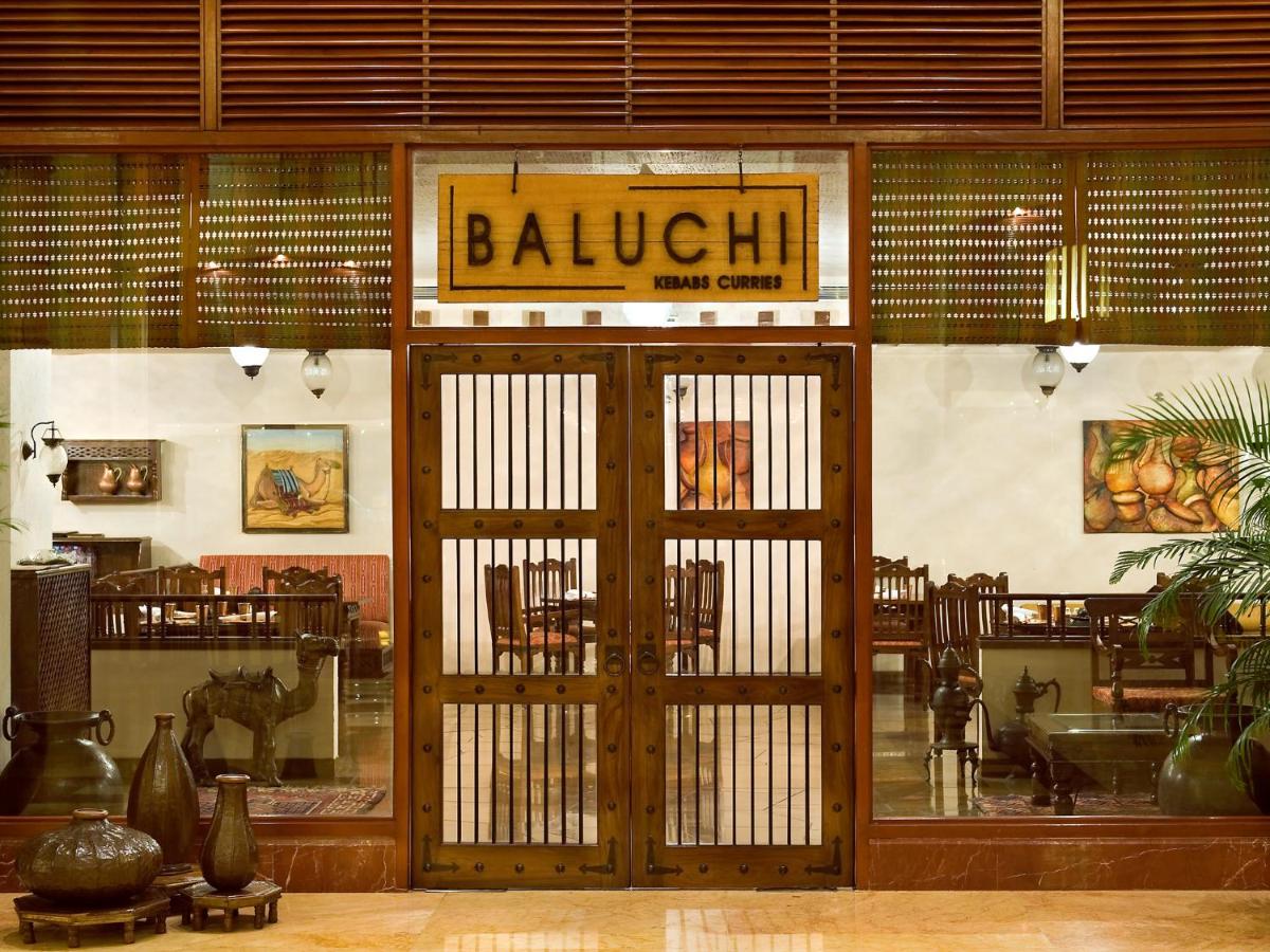 a restaurant with a wooden door with a sign on it at The Lalit Mumbai in Mumbai