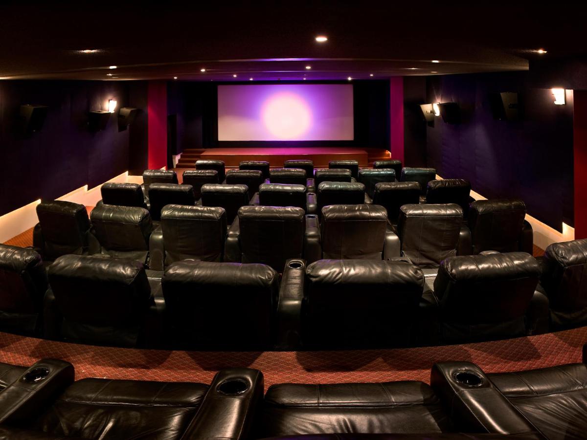an auditorium with black leather chairs and a projection screen at The Lalit Mumbai in Mumbai
