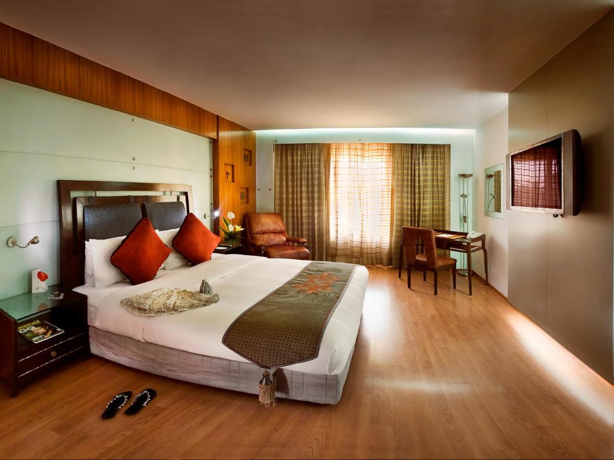 a hotel room with a large bed and a desk at The Lalit Mumbai in Mumbai
