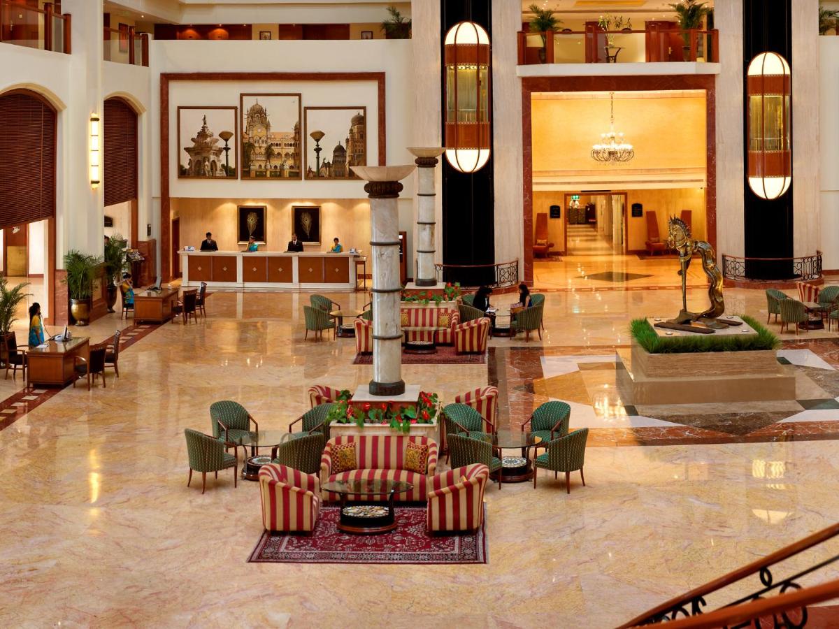 a lobby with chairs and tables in a building at The Lalit Mumbai in Mumbai