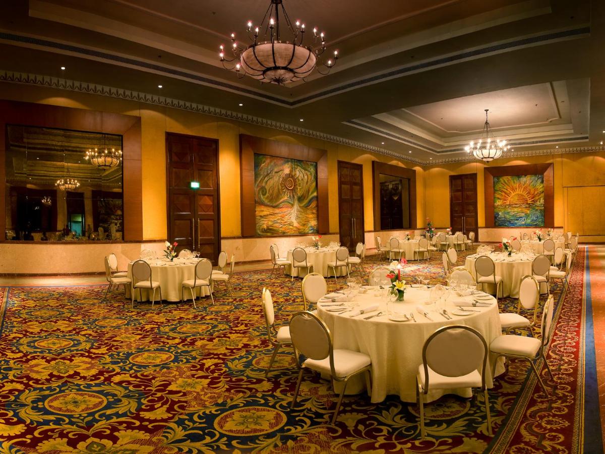 a banquet hall with white tables and white chairs at The Lalit Mumbai in Mumbai