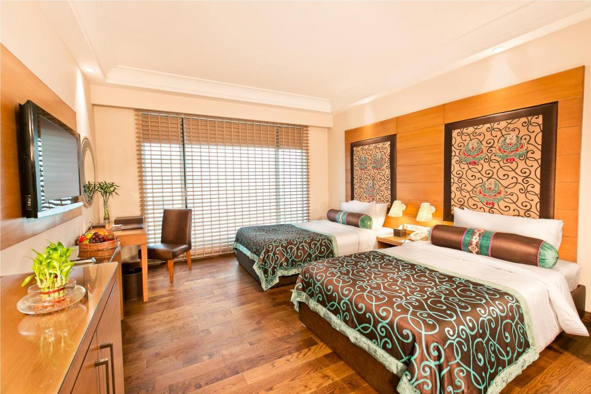 a hotel room with two beds and a television at The Lalit Jaipur in Jaipur