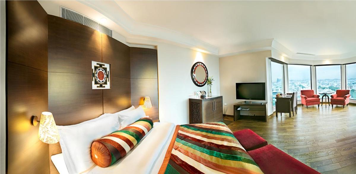 a hotel room with a bed and a living room at The Lalit Jaipur in Jaipur