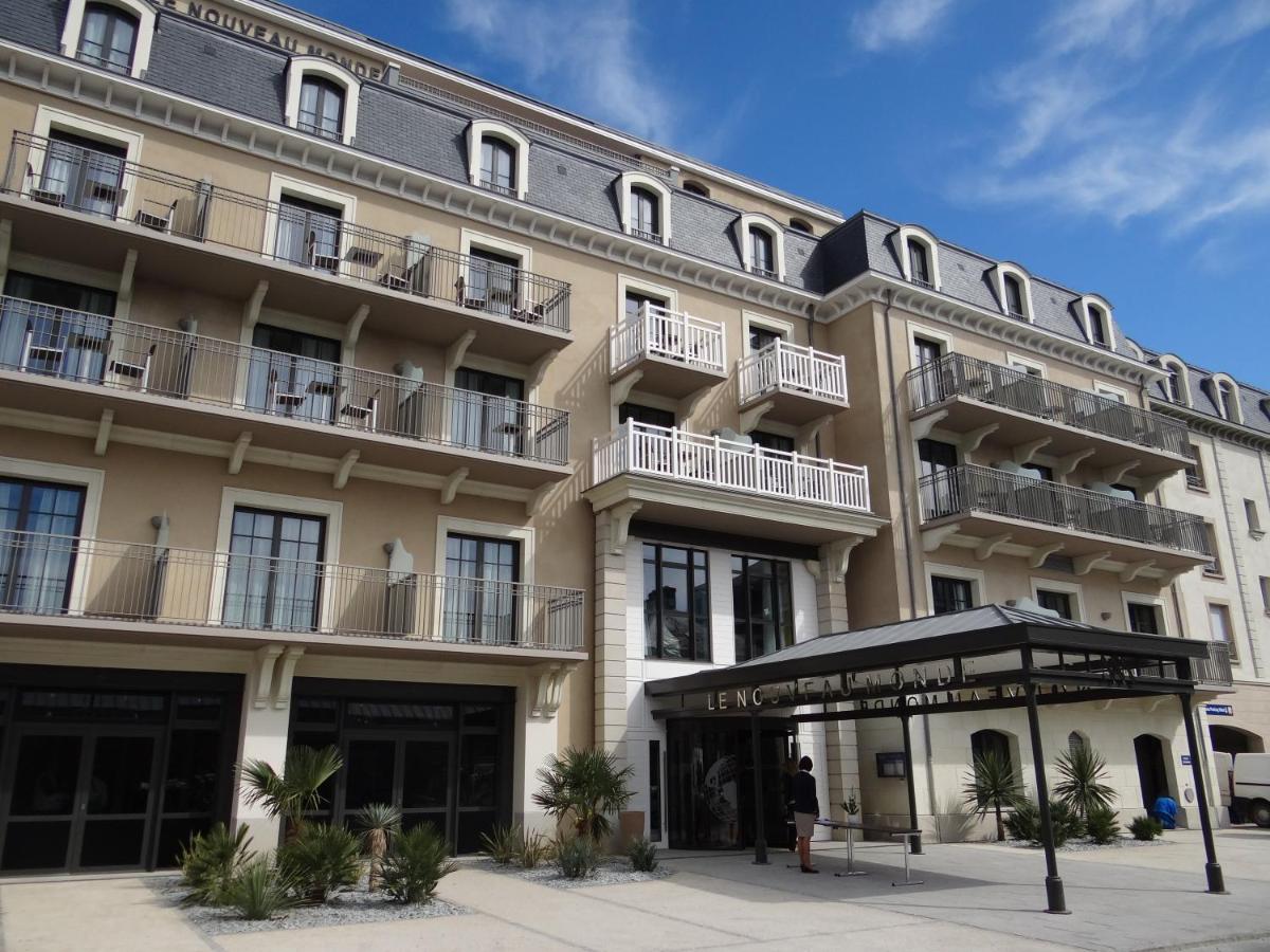 un grand bâtiment avec un homme debout devant lui dans l'établissement Hôtel Le Nouveau Monde, à Saint-Malo