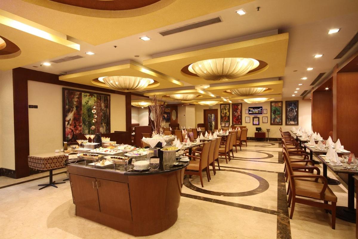 a restaurant with long tables and chairs and chandeliers at Fortune Select JP Cosmos, Bengaluru - Member ITC Hotels' Group in Bengaluru