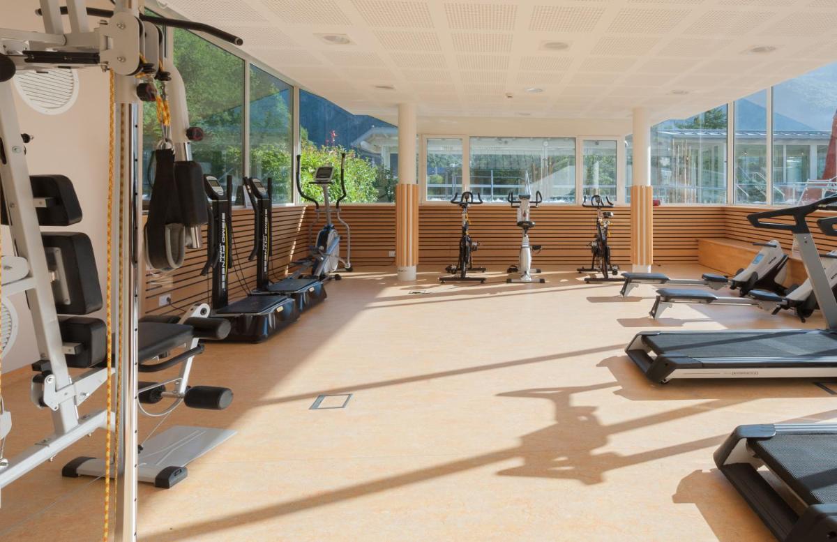 une salle de sport avec une rangée de tapis de course et de vélos elliptiques dans l'établissement Hotel & Spa Radiana, à La Léchère