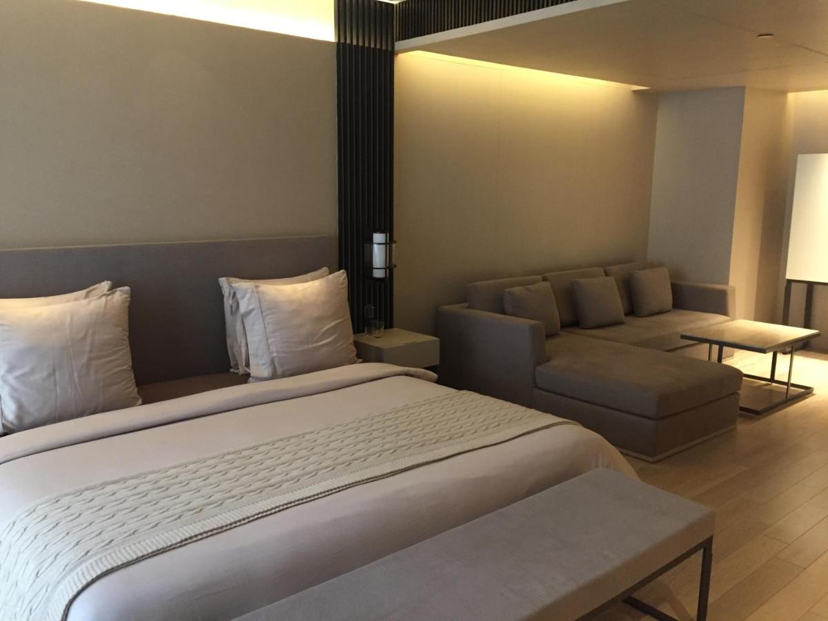 a hotel room with a large bed and a couch at Roseate House New Delhi in New Delhi a hotel room with a large bed and a couch at Roseate House New Delhi in New Delhi