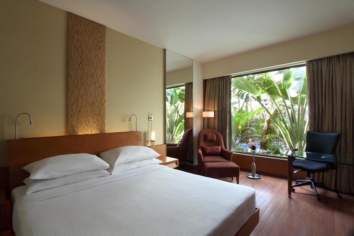 a bedroom with a bed and a desk and a window at Hyatt Pune in Pune