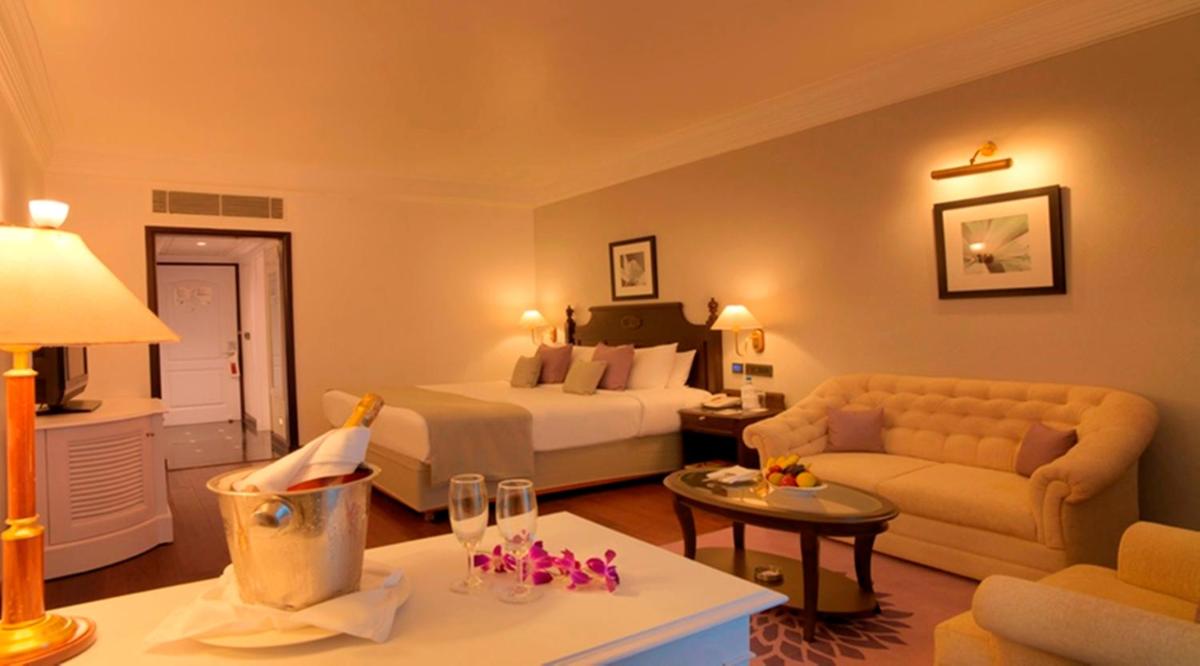 a hotel room with a bed and a couch at Hotel Royal Orchid Bangalore in Bengaluru