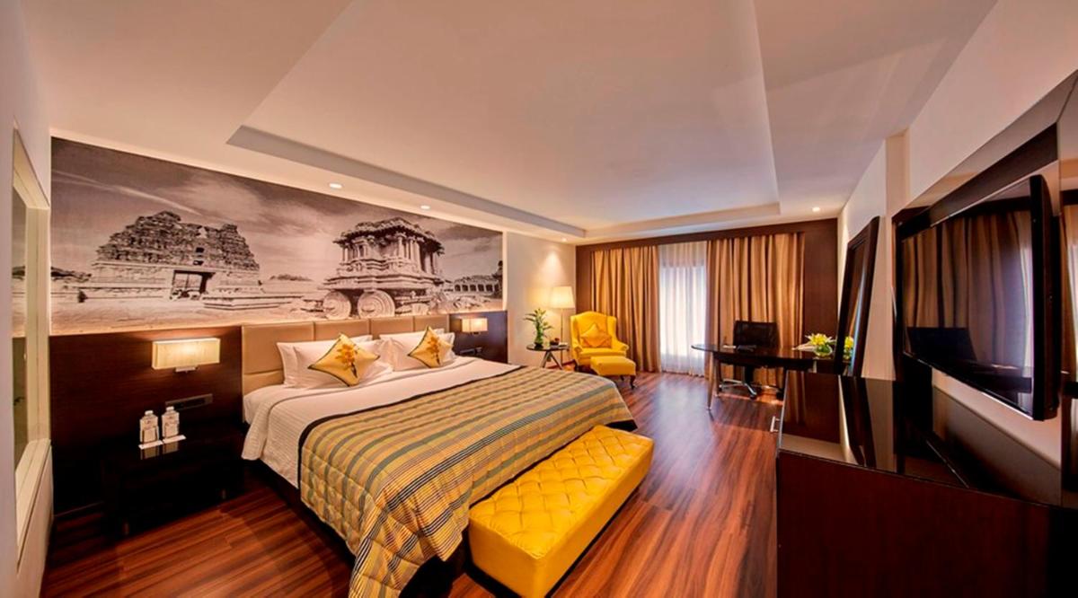 a hotel room with a bed and a television at Hotel Royal Orchid Bangalore in Bengaluru