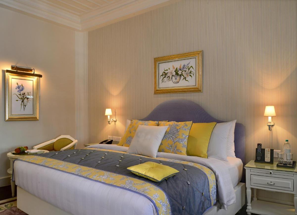 a bedroom with a large bed with yellow and blue pillows at Welcomhotel by ITC Hotels, The Savoy, Mussoorie in Mussoorie